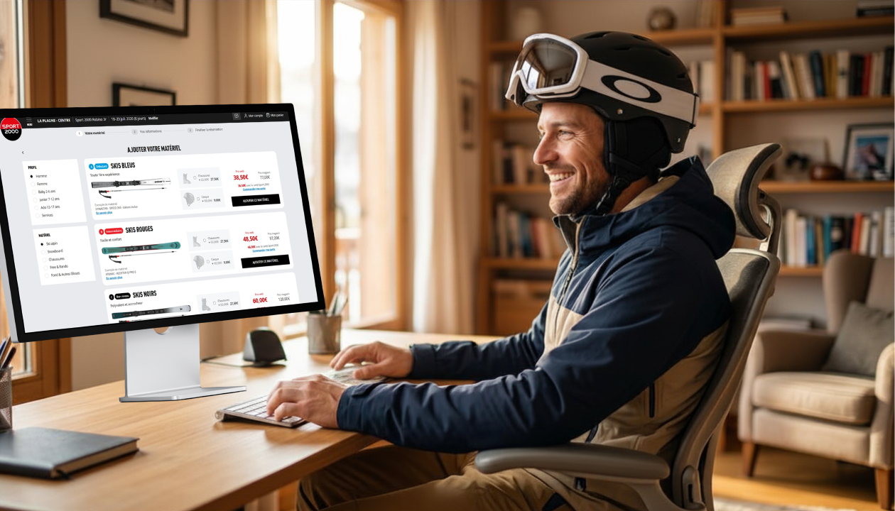 Un homme souriant en tenue de ski loue du matériel sur son ordinateur à la maison.