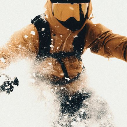Skieur en tenue or dévale une pente pleine de poudreuse